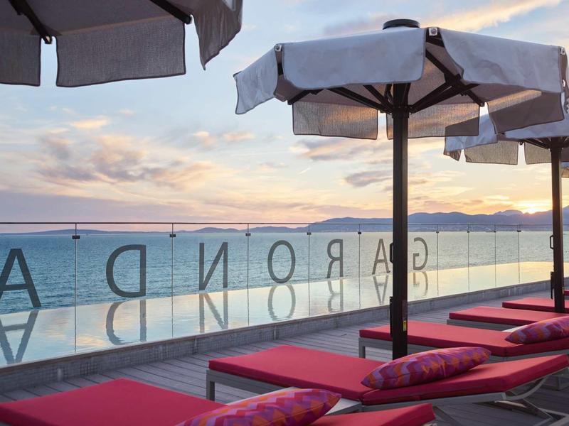 Czerwone leżaki z parasolami na wybrzeżu o zachodzie słońca.