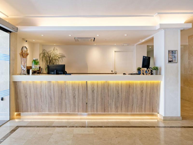 Modern hotel reception with wooden front desk, ambient lighting, and minimalistic decor.