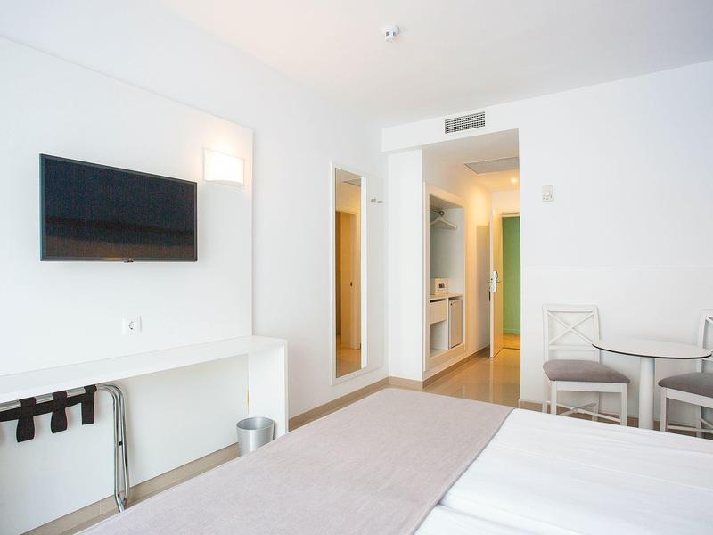 Habitación de hotel moderna con televisión de pantalla plana, sillas y decoración minimalista.