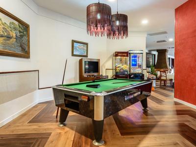 Interno con tavolo da biliardo, panchina in pelle, pavimento in legno duro e luci decorative a soffitto.