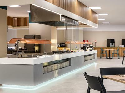 Nowoczesny, jasny bufet w hotelowej jadalni z stołami i krzesłami.