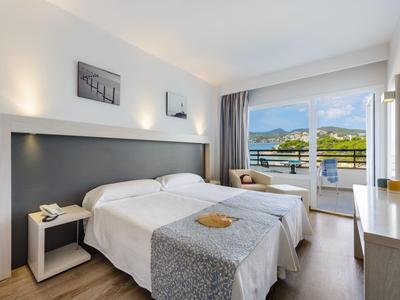 Nowoczesny pokój hotelowy z dwoma łóżkami pojedynczymi i balkonem z widokiem na morze.