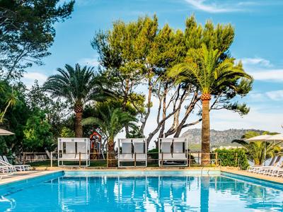 Piscina blu con lettini, palme e cielo azzurro limpido sullo sfondo.