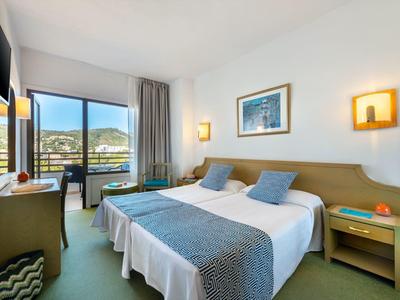 Jasny pokój hotelowy z dwoma łóżkami, widokiem na morze i nowoczesnymi drewnianymi meblami.