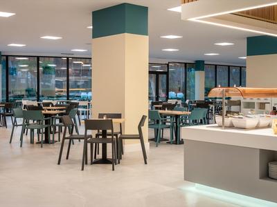 Nowoczesna sala śniadaniowa z stołami, krzesłami i jasnym bufetem.