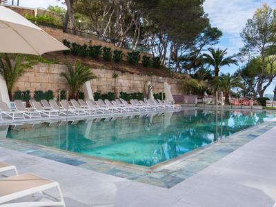 Nowoczesny basen na świeżym powietrzu z białymi leżakami i parasolami w tropikalnym otoczeniu.