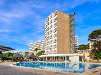 Budynek hotelu z dużym basenem na zewnątrz i parasolami pod niebieskim niebem