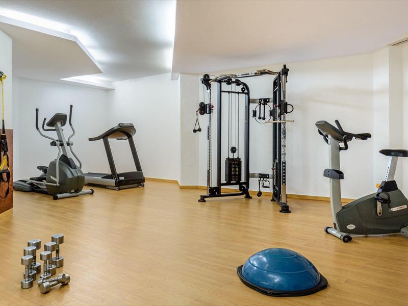 Siłownia z sprzętem fitness w jasnym i czystym pomieszczeniu.