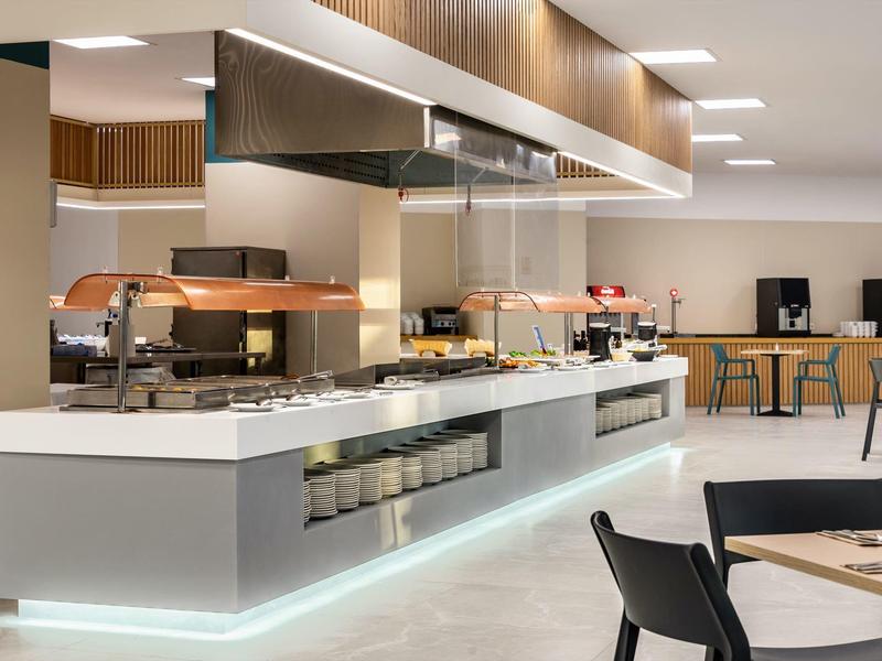 Nowoczesny, jasny bufet w hotelowej jadalni z stołami i krzesłami.