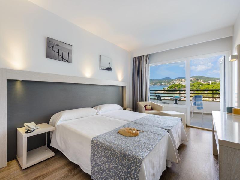 Nowoczesny pokój hotelowy z dwoma łóżkami pojedynczymi i balkonem z widokiem na morze.