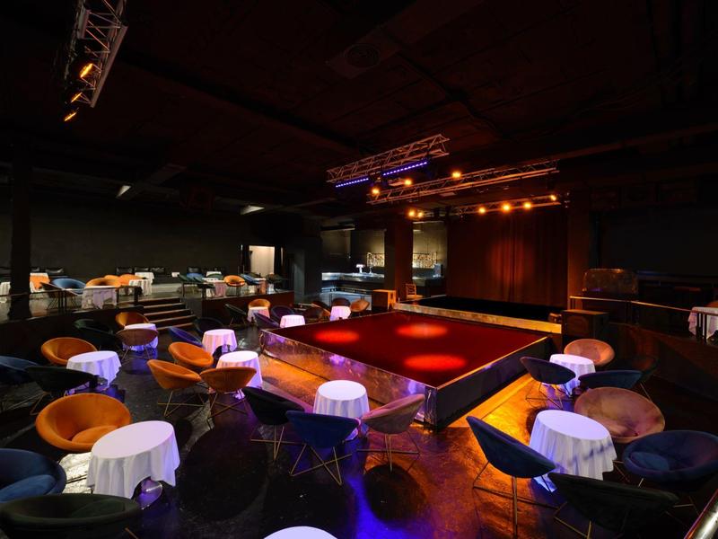 Luksusowa sala widowiskowa z wygodnymi siedzeniami i czerwono oświetloną sceną.