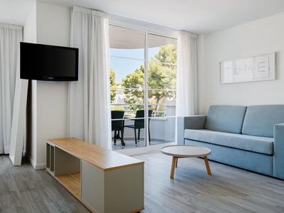 Nowoczesny salon z sofą, stolikiem kawowym, telewizorem i widokiem na balkon z roślinami.