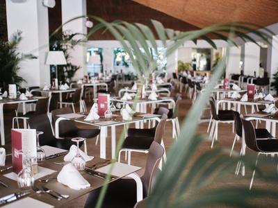 Nowocześnie urządowana restauracja hotelowa z nakrytymi stołami i brązowymi krzesłami.