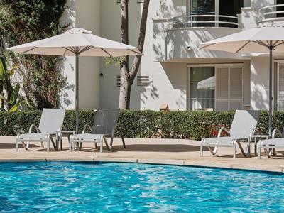 Zwembadzone met ligstoelen en parasols voor een modern hotelgebouw