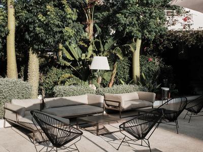 Nowoczesna przestrzeń na zewnątrz z meblami wypoczynkowymi i roślinami do relaksu na świeżym powietrzu.