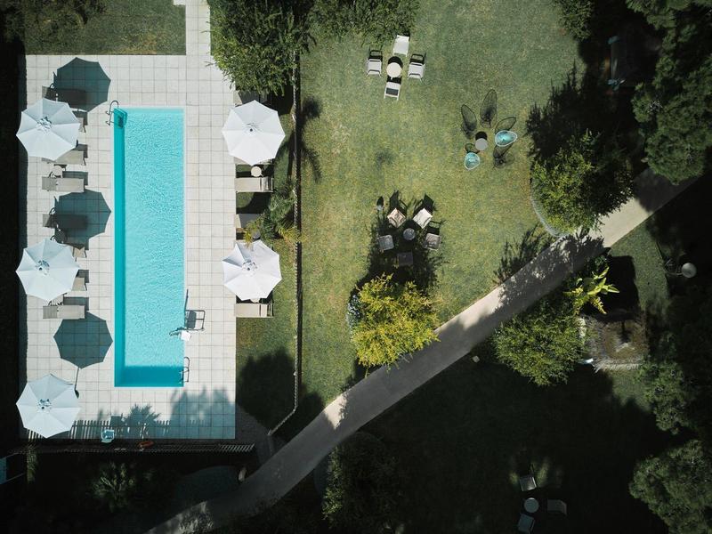 Widok z lotu ptaka na basen z parasolami i miejscami do siedzenia obok ścieżki ogrodowej.