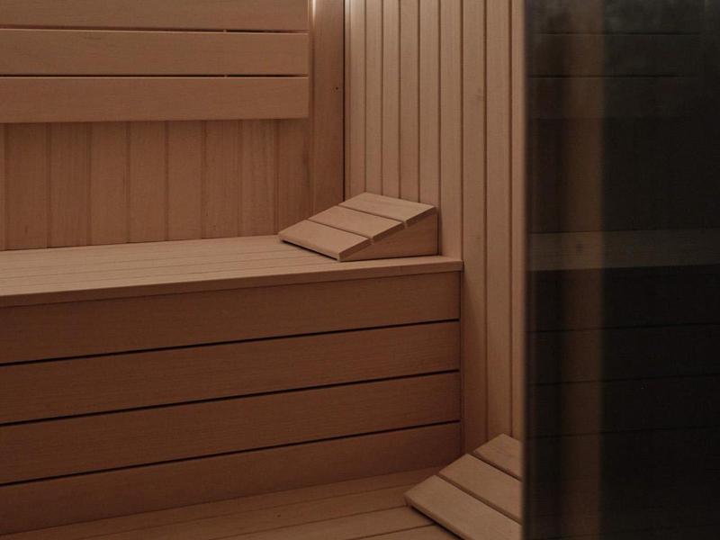 Przytulna sauna fińska z drewnianymi ławkami i stłumionym światłem.