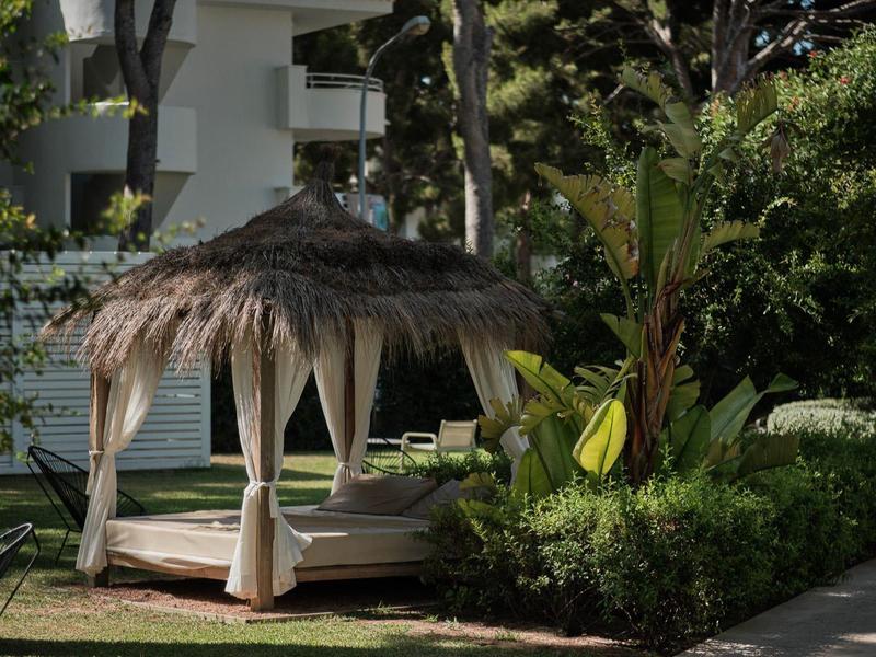 Zadaszona altana z zasłonami w ogrodzie obok budynku hotelu.