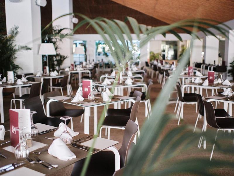 Nowocześnie urządowana restauracja hotelowa z nakrytymi stołami i brązowymi krzesłami.