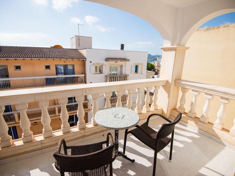 Balkon mit Tischen und Stühlen mit Blick auf benachbarte Gebäude bei Tageslicht.