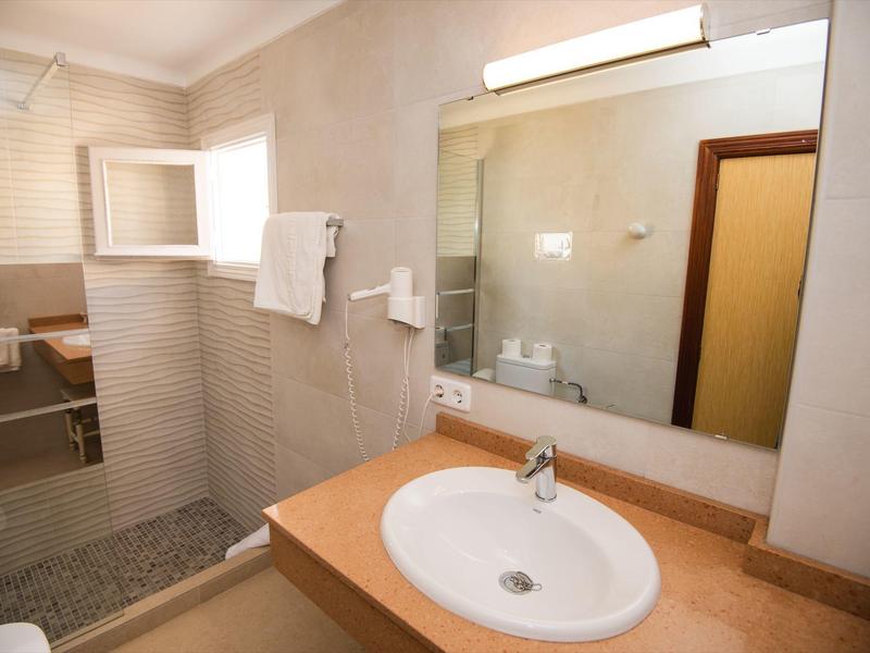 Modernes Badezimmer mit Waschbecken, großem Spiegel und begehbarer Dusche mit Handtüchern.