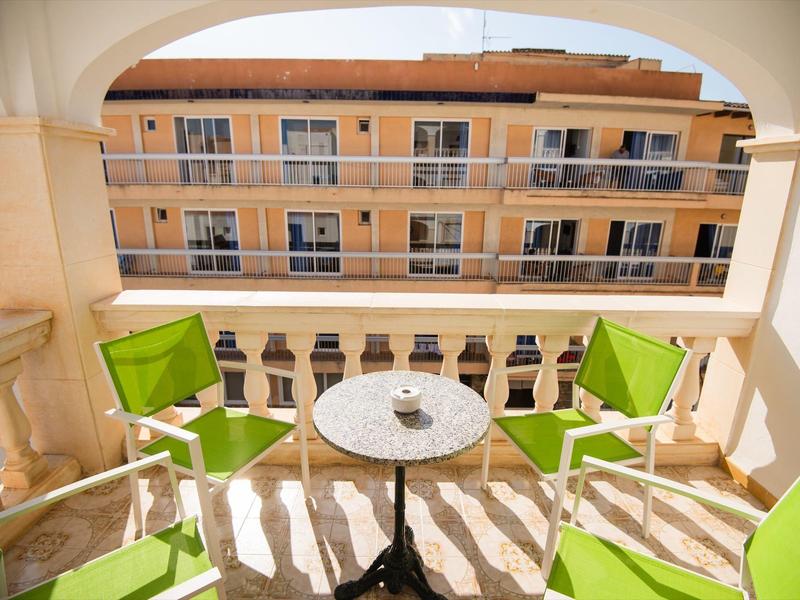 Balkon mit grünem Mobiliar und kleinem runden Tisch mit Blick auf angrenzendes Gebäude.