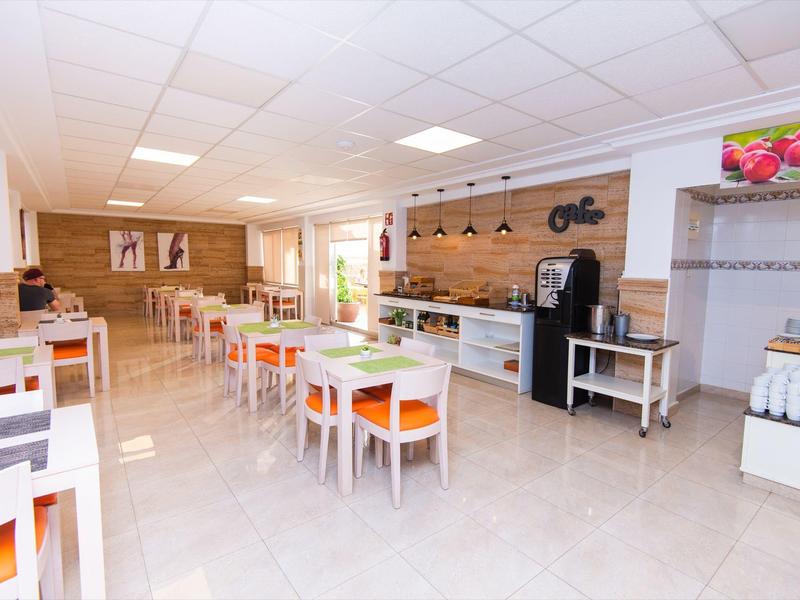 Helles, modernes Café mit weißen Tischen und orangefarbenen Stühlen, Holzverkleidung an der Wand.