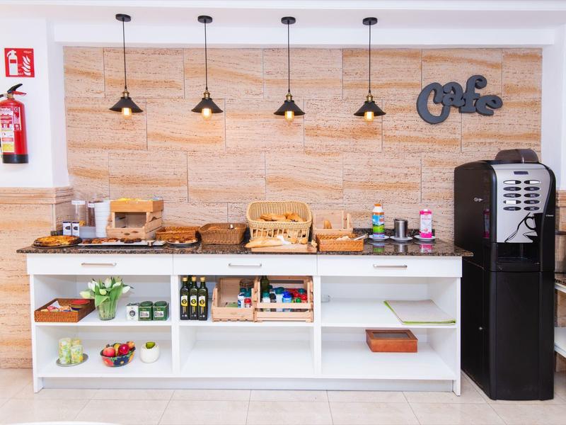 Frühstücksbereich mit Kaffeemaschine, Brotkorb und frischen Früchten in modernem Design.