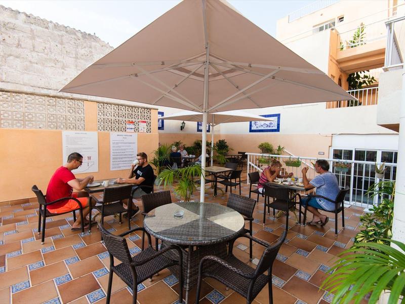 Außenbereich einer Terrasse mit Tischen, Stühlen und Sonnenschirmen in einem Hotel.