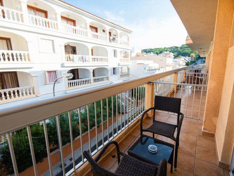 Balkon mit zwei Stühlen und Tisch mit Blick auf benachbarte Gebäude bei Tageslicht.