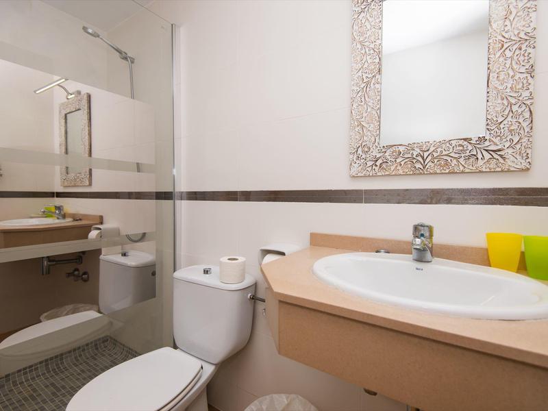 Kleines Badezimmer mit Waschbecken, Toilette und großem Spiegel mit dekorativem Rahmen.