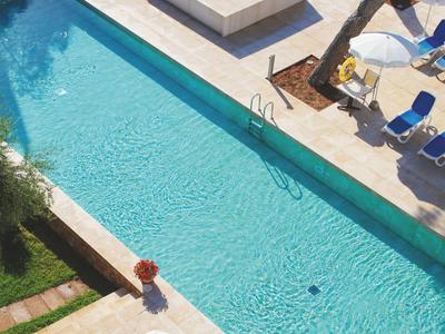 Modern outdoor pool with two hot tub areas and sun umbrellas on the terrace.