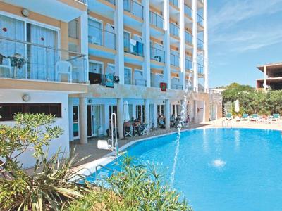 Grande hotel con camere con balcone e ampio piscina all'aperto con tempo soleggiato.