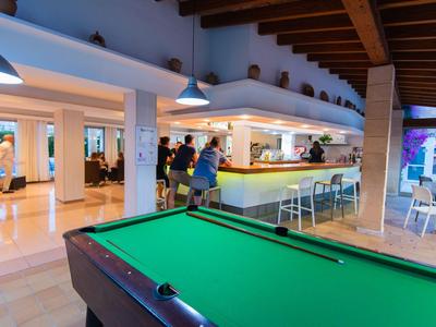 Moderní hotelová lounge s kulečníkovým stolem, barem a posezením pod dřevěným stropem.