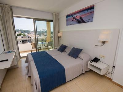 Helles Hotelzimmer mit Doppelbett, Balkon mit Meerblick und moderner Einrichtung.