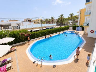 Hotelpool mit blauer Wasserfläche, umliegenden Liegen und Gästen bei sonnigem Wetter.