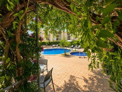Hotelgarten mit begrüntem Bogen und Pool im Hintergrund