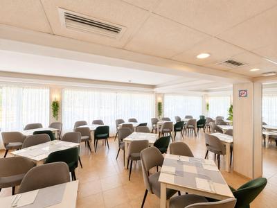Helles, modern eingerichtetes Restaurant mit grauen Stühlen und quadratischen Tischen.