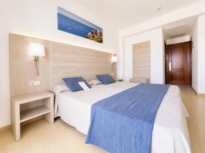 Modernes Hotelzimmer mit großem Bett, blauer Bettdecke, Holzdekor und seitlicher Nachttischlampe.