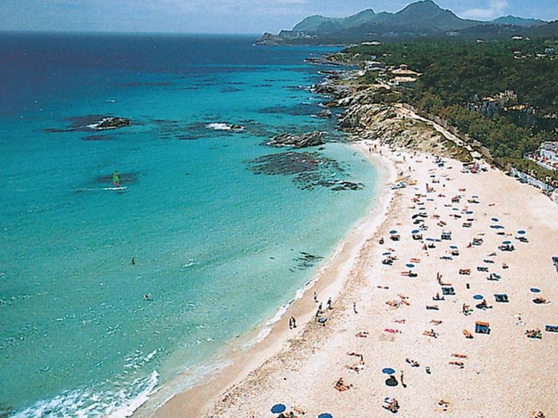 Lunga spiaggia sabbiosa con acqua turchese e molti ombrelloni lungo una costa.