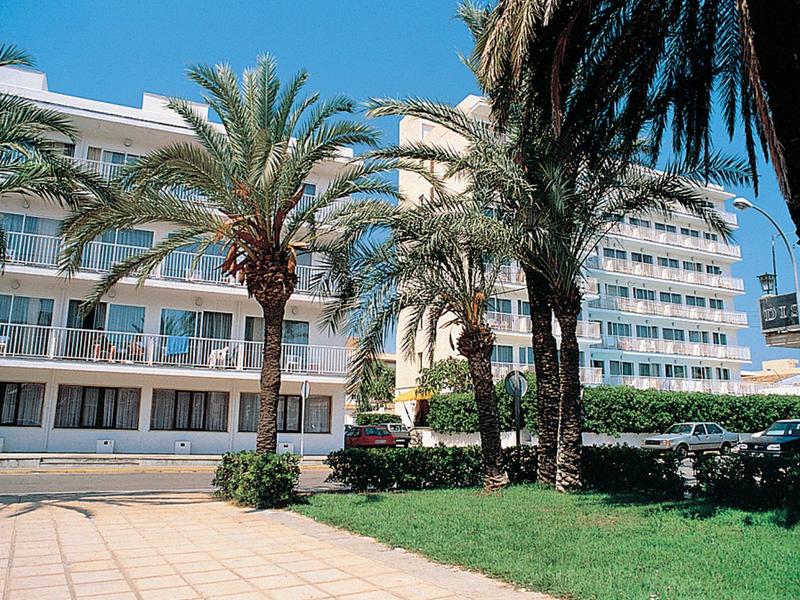 Edificio dell'hotel con palme e prato curato sotto un cielo azzurro limpido