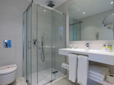 Modernes Badezimmer mit glasdichter Dusche, weißer Toilette und großem Spiegel über Waschbecken.
