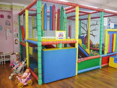 Bunter Indoor-Spielplatz mit Klettergerüst, Rutsche und Spielfläche in einem Kinderzimmer.