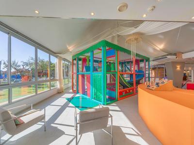 Jasny plac zabaw w hotelowym salonie z dużymi oknami.