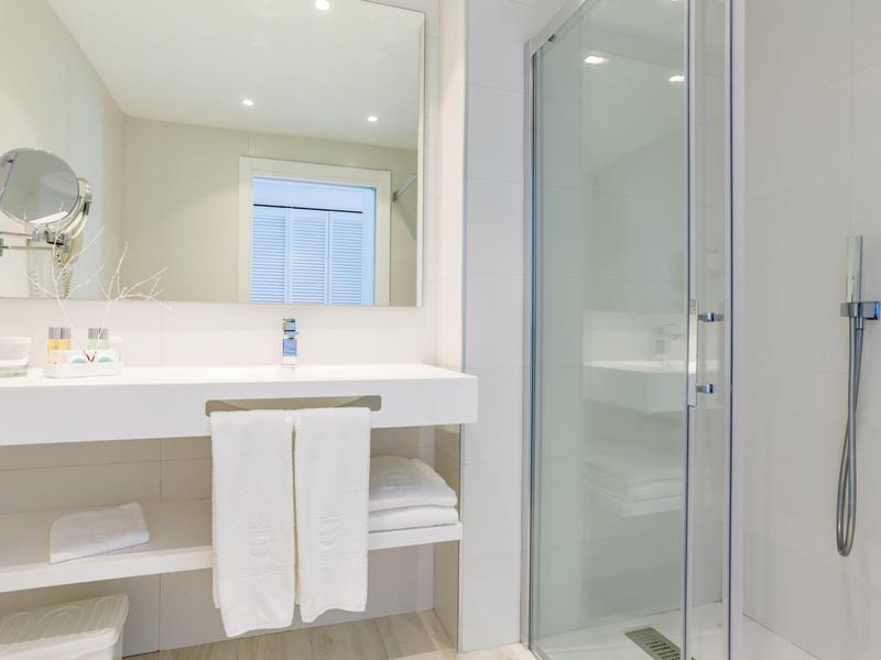 Czysta, nowoczesna łazienka z dużym lustrem, umywalką i oddzielnym prysznicem.