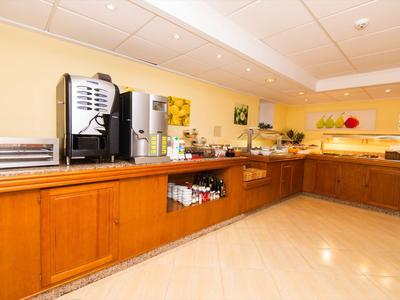 Buffet mit Kaffeeautomaten und Frühstücksauswahl in einem hellen Hotelraum.