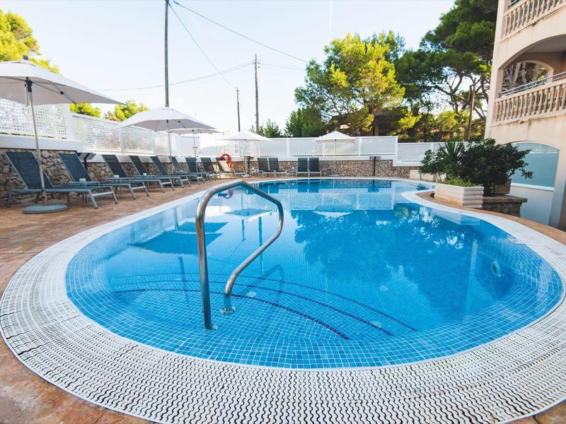 Runder Außenpool mit Stufen und Liegestühlen unter Sonnenschirmen auf der Terrasse.