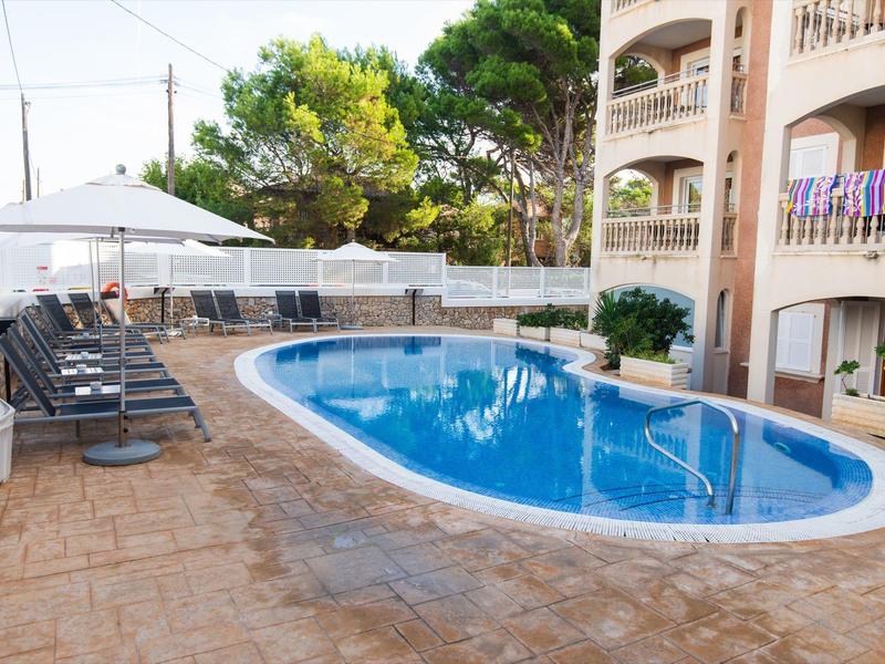 Poolbereich mit Sonnenliegen, Sonnenschirm und angrenzendem Gebäude bei Tageslicht