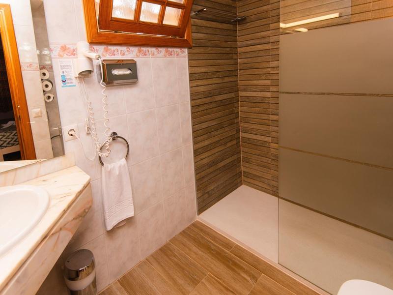 Modernes Badezimmer mit Waschbecken, Handtuchhalter, Duschbereich und braunen Fliesen.