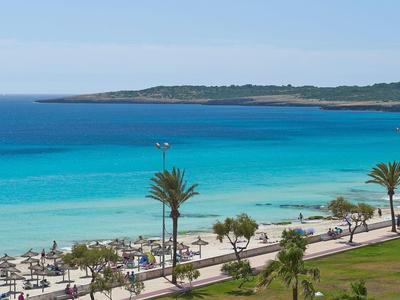 Pohled na slunnou pláž s palmami a tyrkysovým mořem.